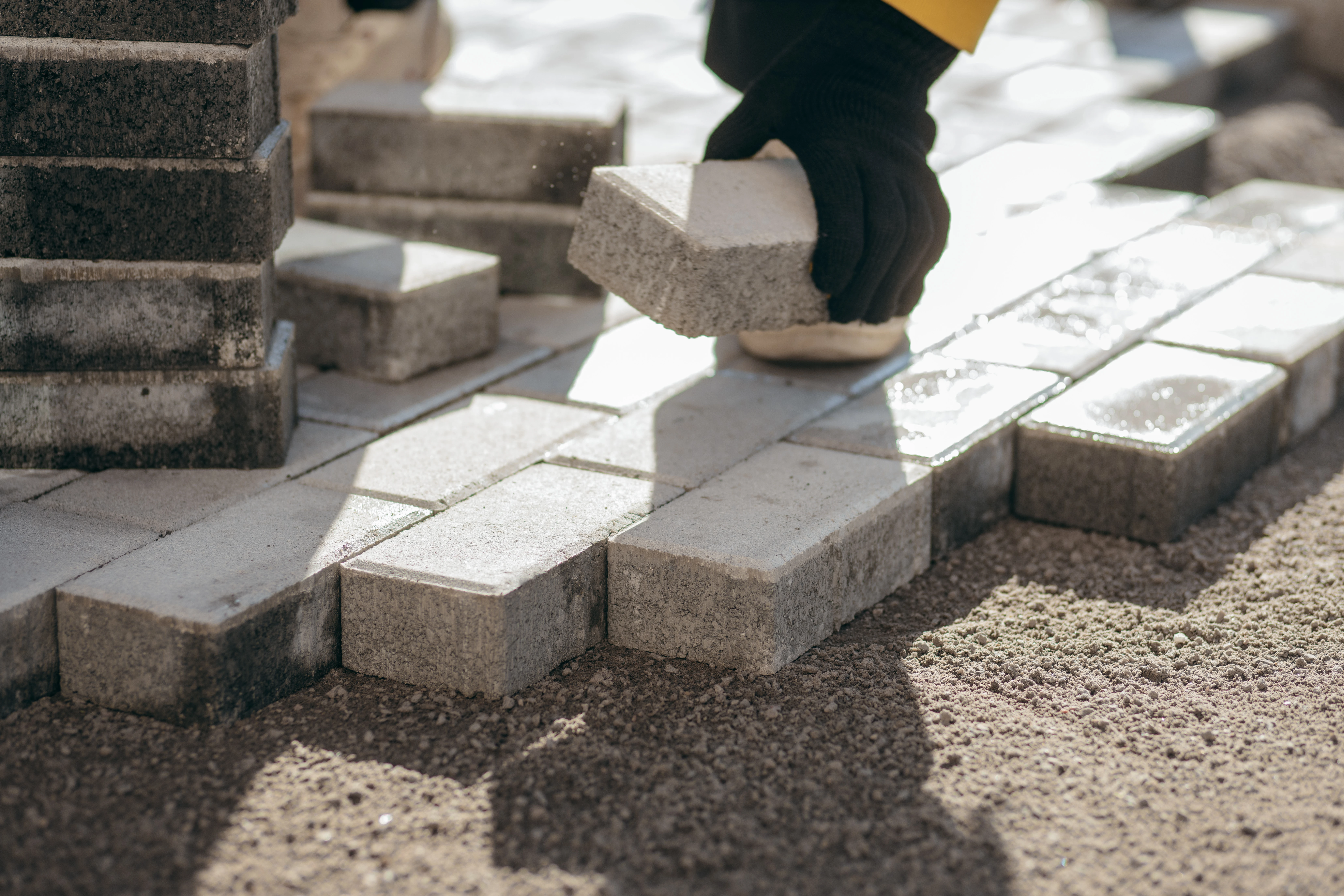 A person is laying down rectangular bricks on a surface, with a focus on hand placement and arranged bricks.